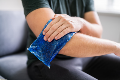 man applying gel ice pack to arm